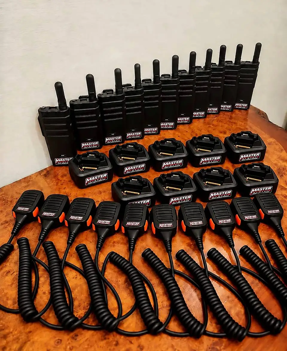 Master System radios, charging docks and speaker mics lined up on a table, each with the Master System label