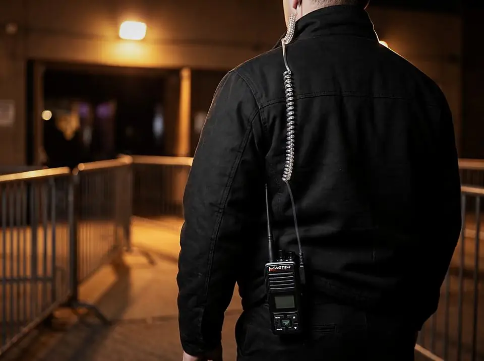 Security officer seen from behind with a radio and earpiece